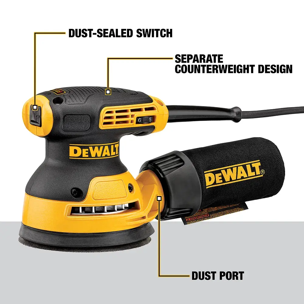 A person wearing a dust mask and safety glasses is using a DEWALT DWE6423 electric sander to smooth a wooden panel in a workshop. Various woodworking tools and cabinets are visible in the background.