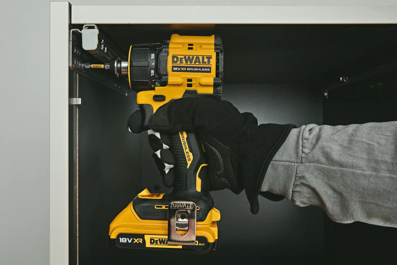 DEWALT drill DCD803NT-XJ, DCD803NT in use inside cabinet. Photography product category. Gloved hand visible.