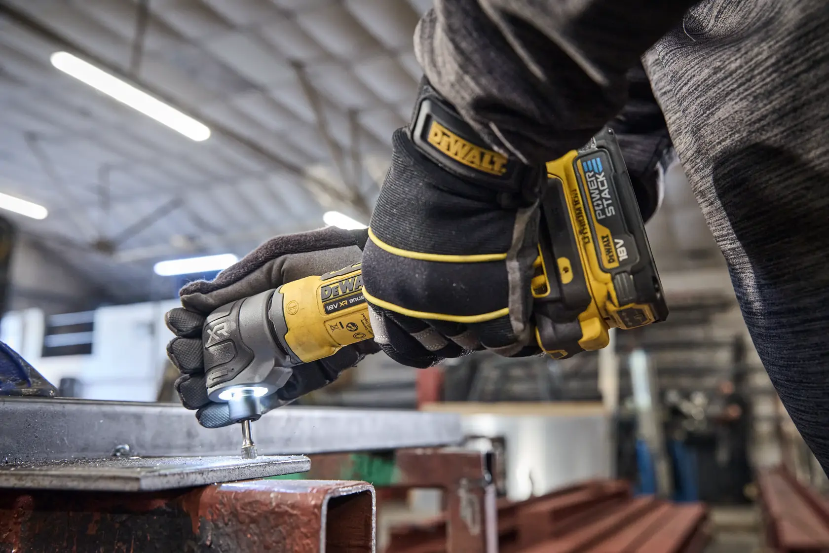 Worker uses DEWALT tool DCG421N-XJ, DCG421N on metal in workshop.