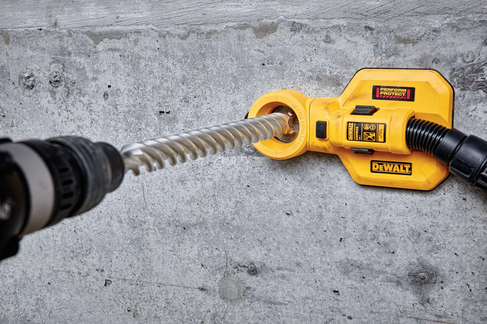 DEWALT drill with dust extraction attachment in use on a concrete wall.