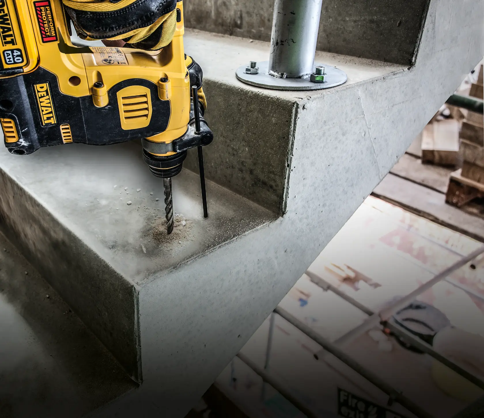 DEWALT drill in use, drilling into concrete stairs at a construction site. Dust visible around the drill bit.
