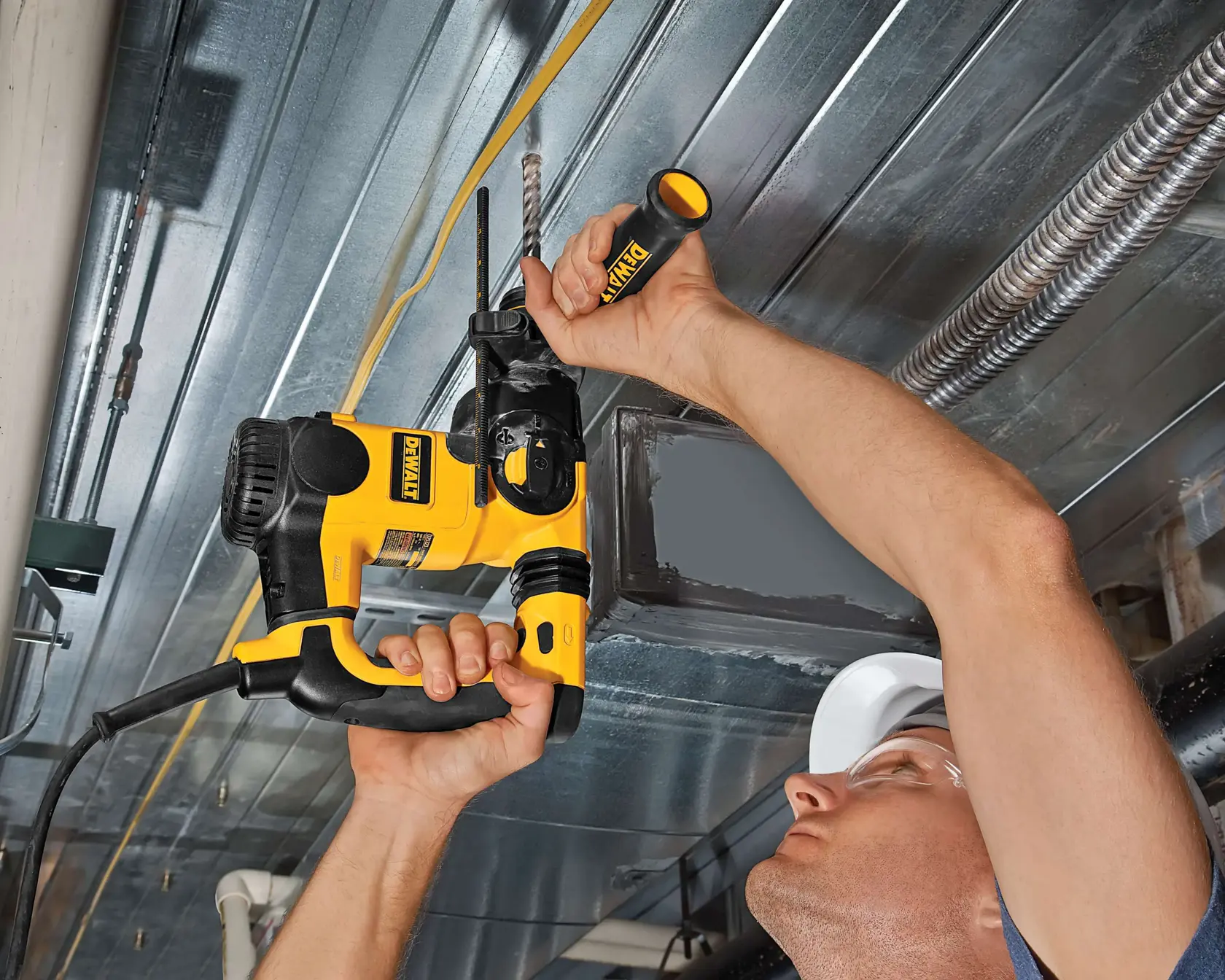 Person using a DEWALT drill to bore into a metal ceiling, showing tool in action.